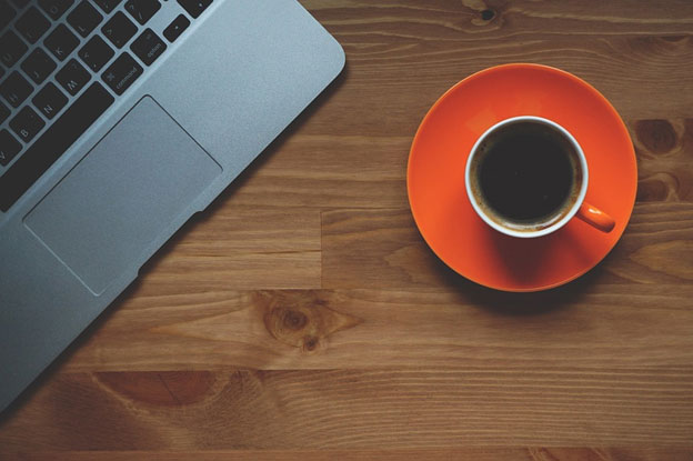 A computer and a cup of coffee on a table