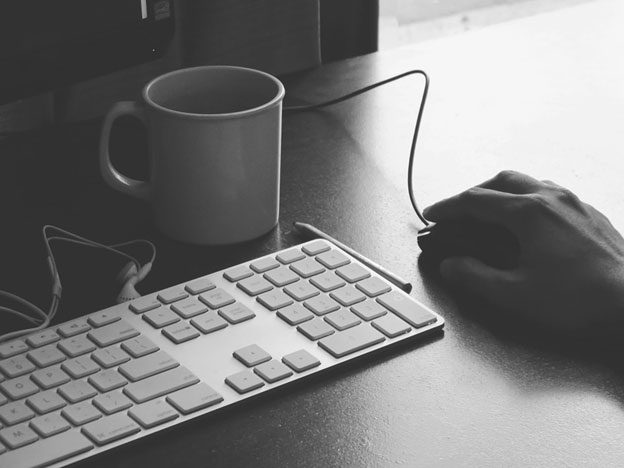 Apple keyboard with hand on mouse