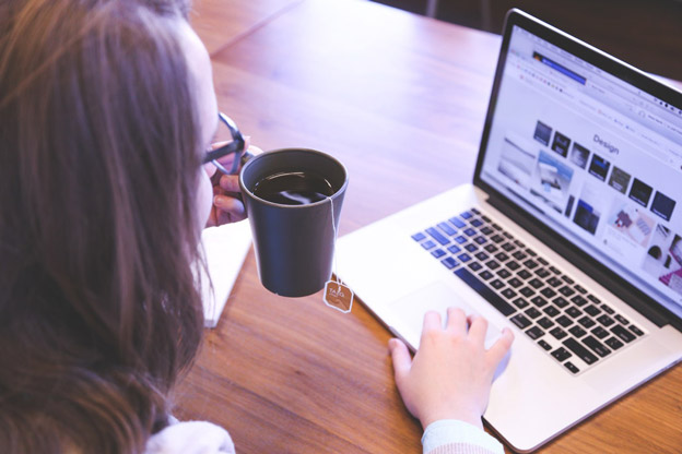 a woman drinks tea and uses a computer